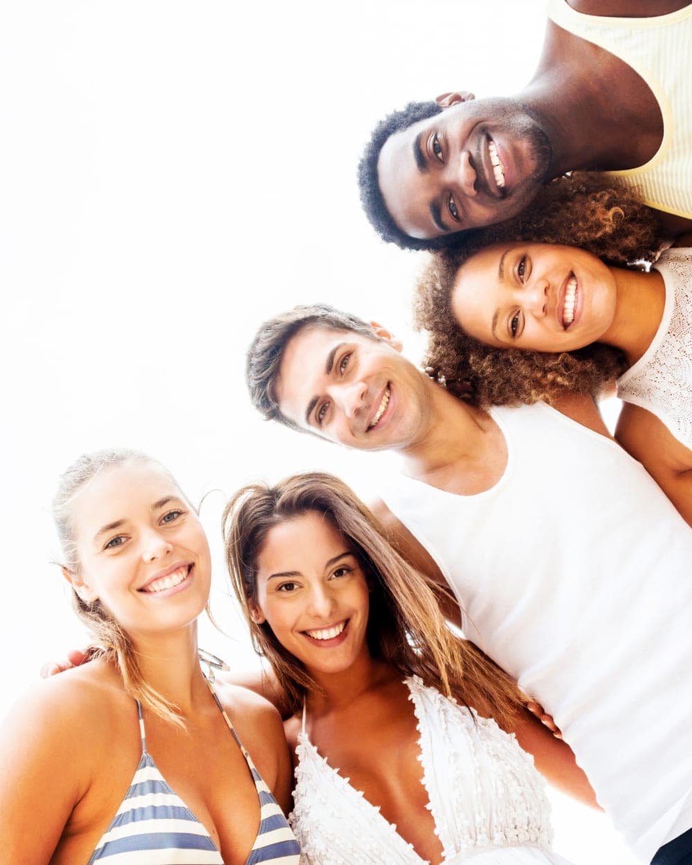 A group of friends huddled together smiling on a bright summer day